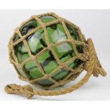 Green glass buoy in rope basket, diameter 13cm approx.