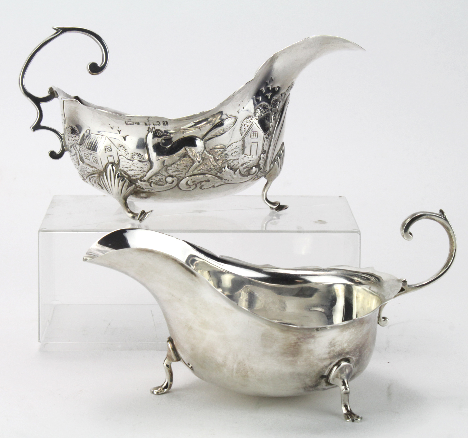 Two silver sauceboats, one plain; hallmarked Chester, 1913 & one decorated with various scenes which
