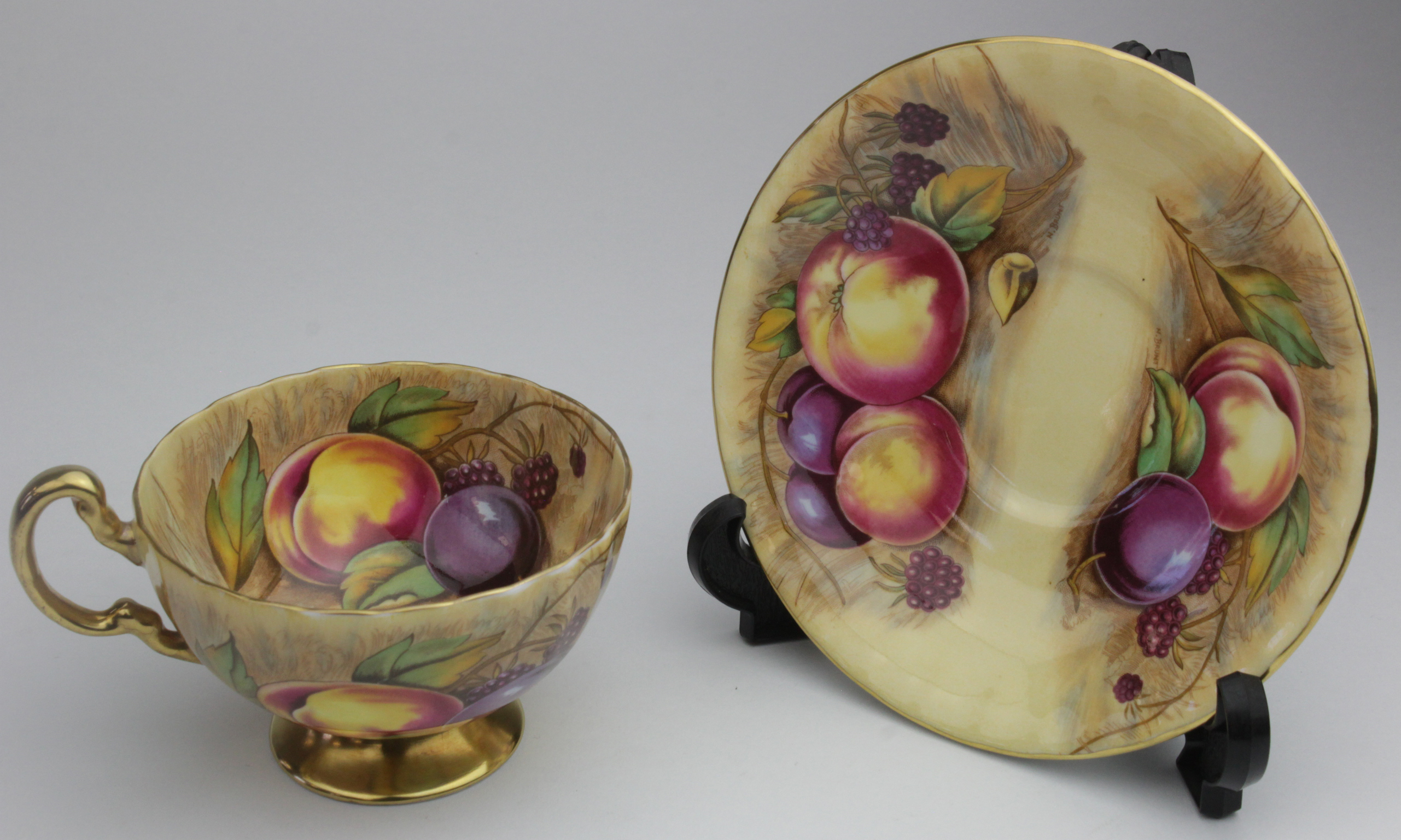 Aynsley. A cup and saucer by Aynsley, with fruit and gilt decoration, each piece bear the