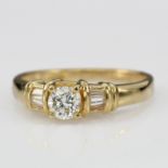 18ct yellow gold ring set with central round brilliant cut diamond with baguette set shoulders,