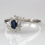 14ct white gold ring set with oval sapphire and approx. 0.25ct of diamonds in a wraparound design,