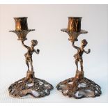 Pair of continental white metal small figural candlesticks cast as cherubs holding aloft the sconce,