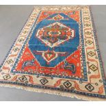 A Kazak hand-knotted carpet decorated with a geometric central medallion upon a blue ground & within