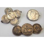 Three silver coin brooches.