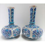 Pair of Iznik bottle vases painted in blue and turquoise with stylised flowers, height 26cm.