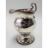Early George III silver cream pedestal jug with gadrooned rim & scroll handle, the body with