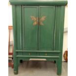 Oriental green painted floor standing cupboard, the hinge lidded doors enclosing two shelves & two