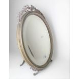 Oval silver plated easel mirror with bevel edged glass, surmounted by a ribbon, bow & acorn leaf