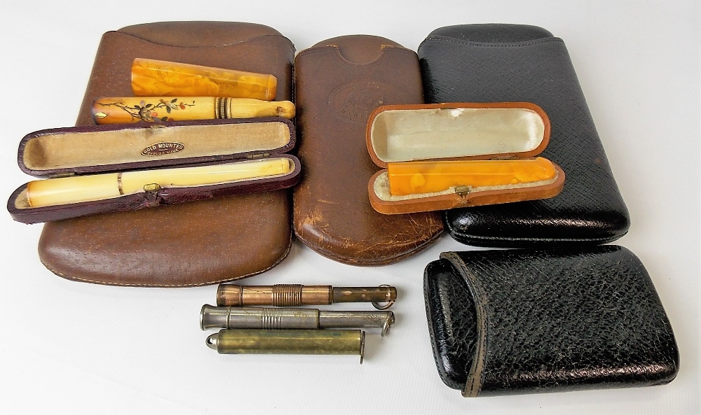 Collection of antique smoking-related items, including two amber cheroot holders, an ivory gold