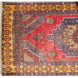 Middle Eastern wool rug with central stepped medallion and flowerheads within borders and with a