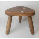 Oak milking stool by Robin Nance of St Ives, with triangular shaped seat, stamped mark to the