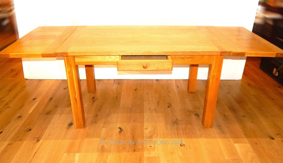 A contemporary honey oak extending dining table