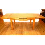 A contemporary honey oak extending dining table