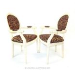 A pair of Louis XVI style white framed upholstered elbow chairs.