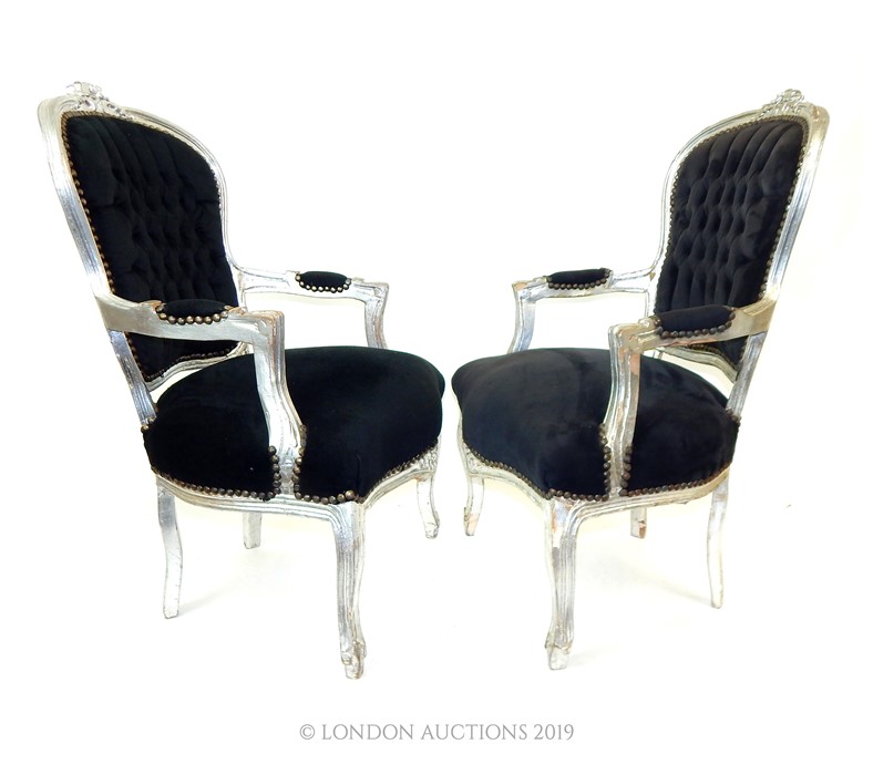 A pair of Louis XVI style black framed upholstered elbow chairs.