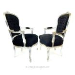 A pair of Louis XVI style black framed upholstered elbow chairs.