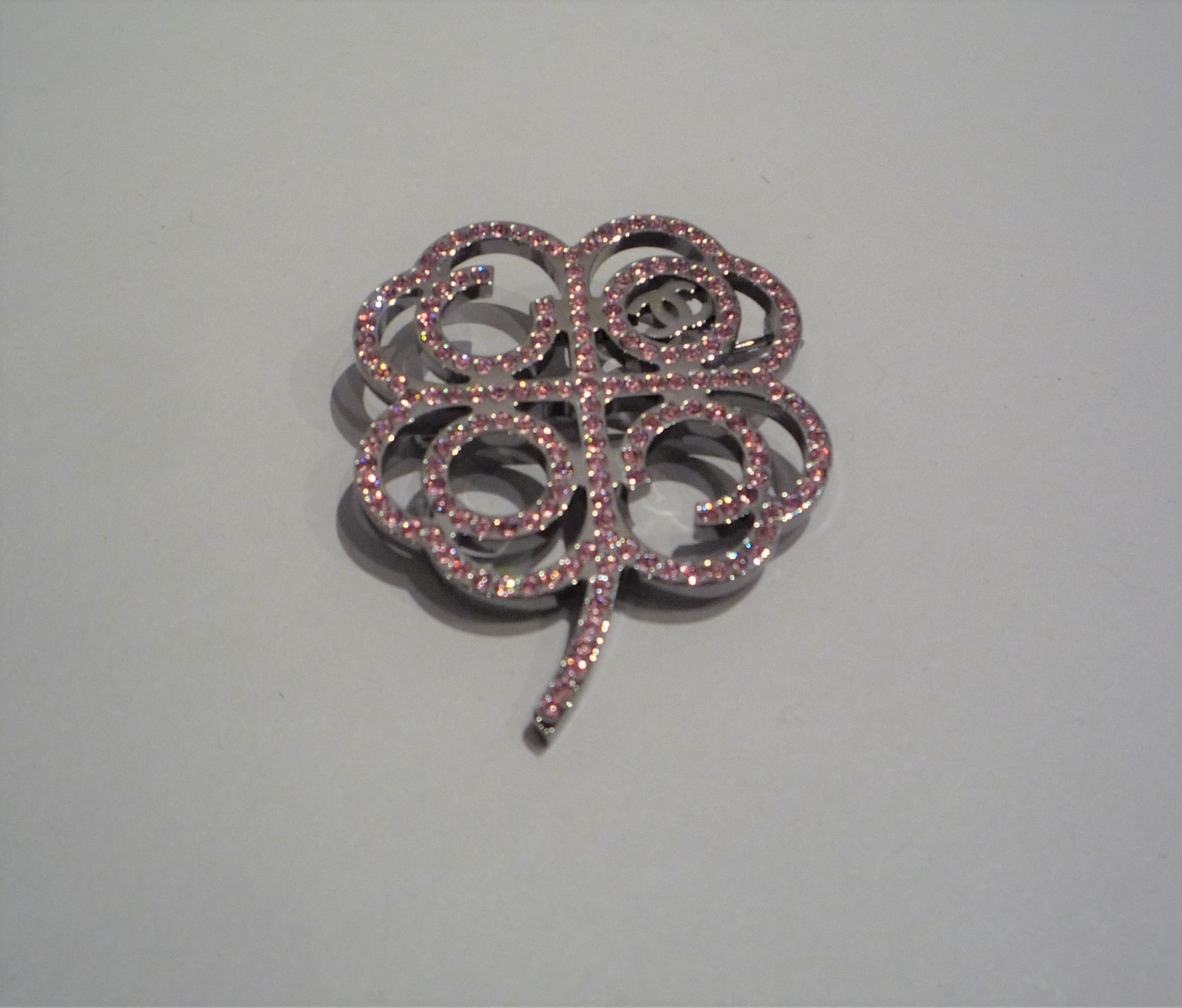 CHANEL - BROCHE en métal argenté incrusté de strass roses figurant une fleur. [...]