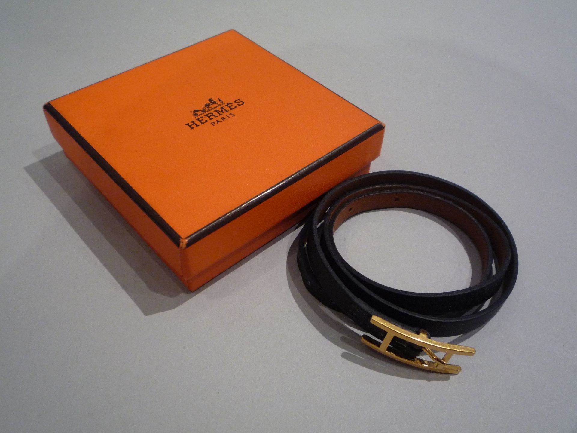 HERMES - Bracelet en cuir noir et boucle H en métal doré. Signé. T.Small. [...]