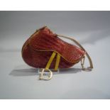 CHRISTIAN DIOR - SAC SELLE en cuir enduit façon crocodile rouge et jaune. Garniture [...]