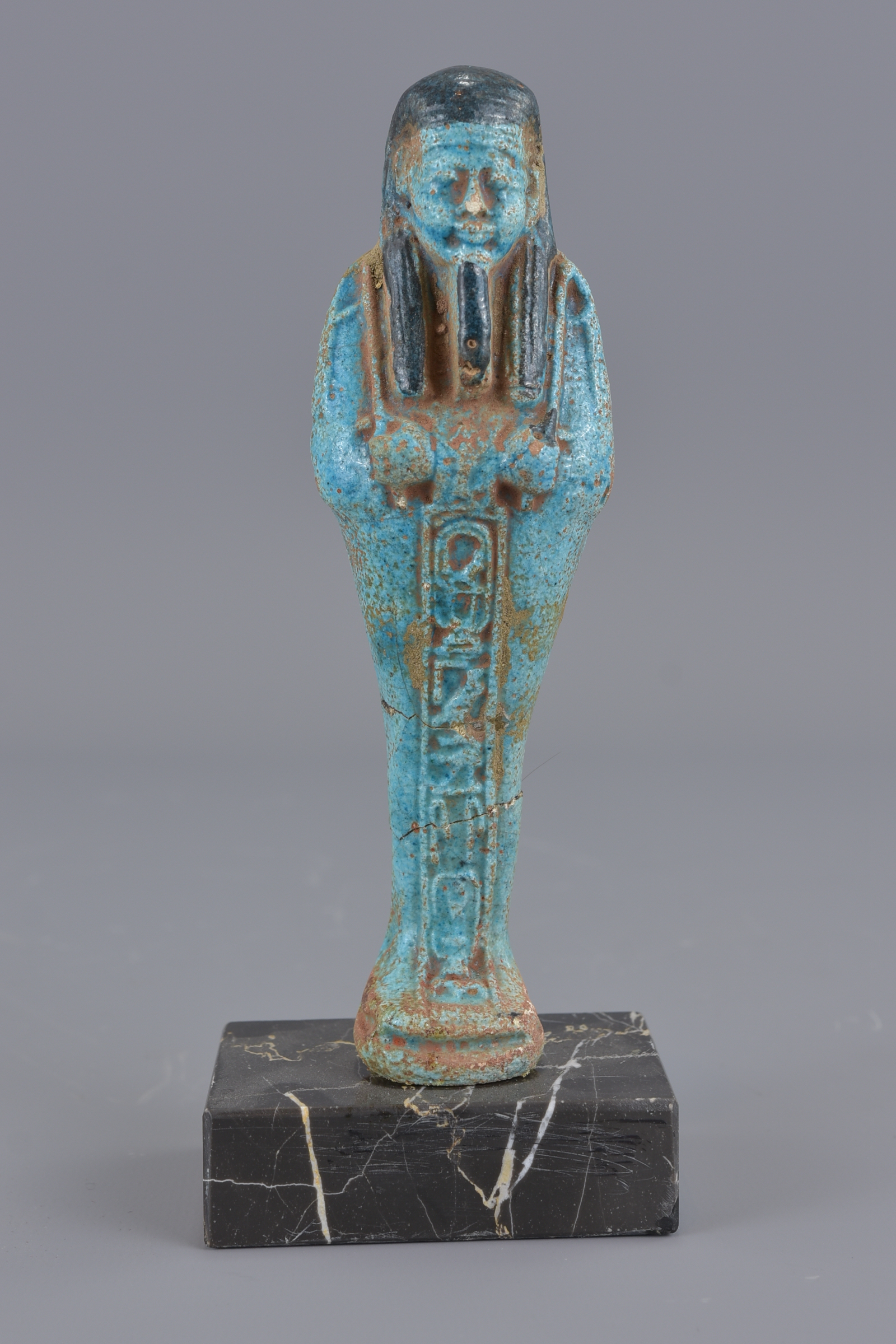 An Egyptian blue faience figure on marble stand. 1