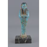 An Egyptian blue faience figure on marble stand. 1