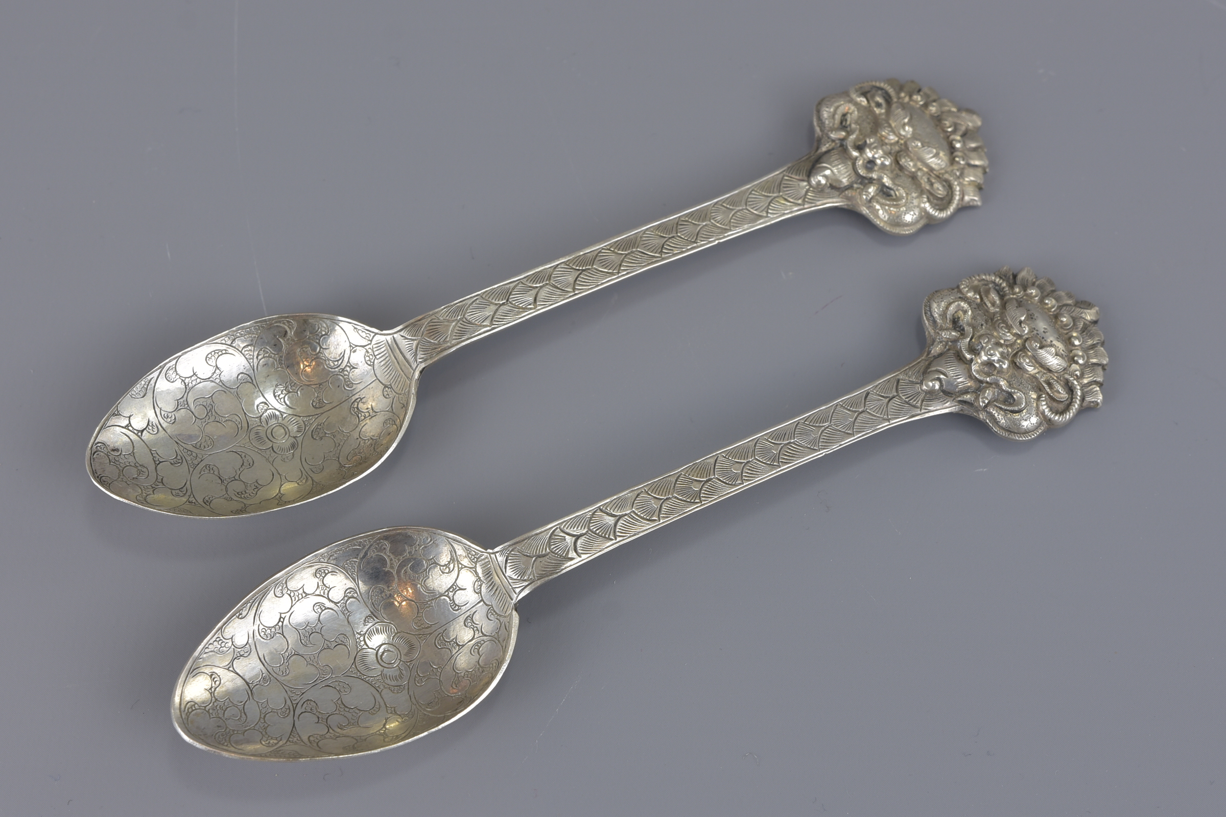 A pair of South East Asian mask head silver spoons