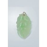 A carved jadeite pendant in the form of a leaf.