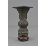A Chinese Ming dynasty style Gu shape bronze beaker with wooden stand. 19cm with stand.