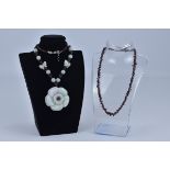 One garnet bead Necklace together with one Jade bead necklace with carved flower pendant.