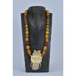 An Ivory Pendant on Amber colour beaded necklace. Pendant 9cm length.