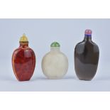 Three 20th century Chinese Snuff Bottles with Stoppers. Glass, Agate and Stone. 6cm - 8.5cm tall (3)