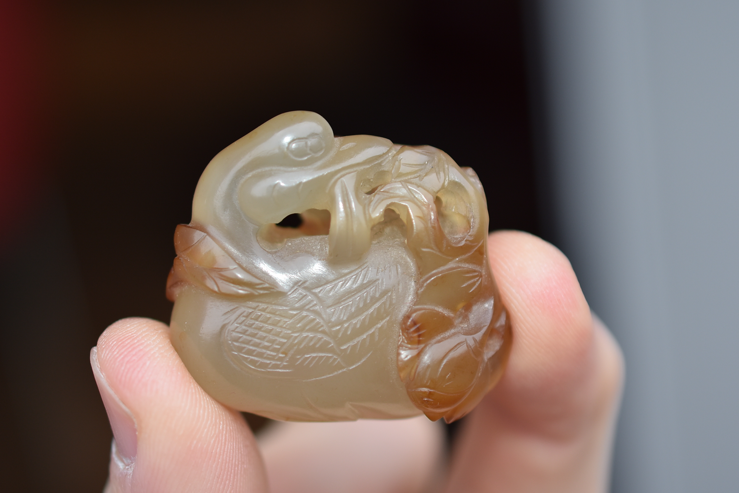 A 19th century Chinese light and dark brown Agate pendant carved as a Duck holding a lotus branch in - Image 11 of 14