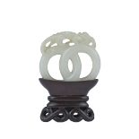 A 19th century Chinese carved White Jade joined rings surmounted by a dragon attached to wooden stan