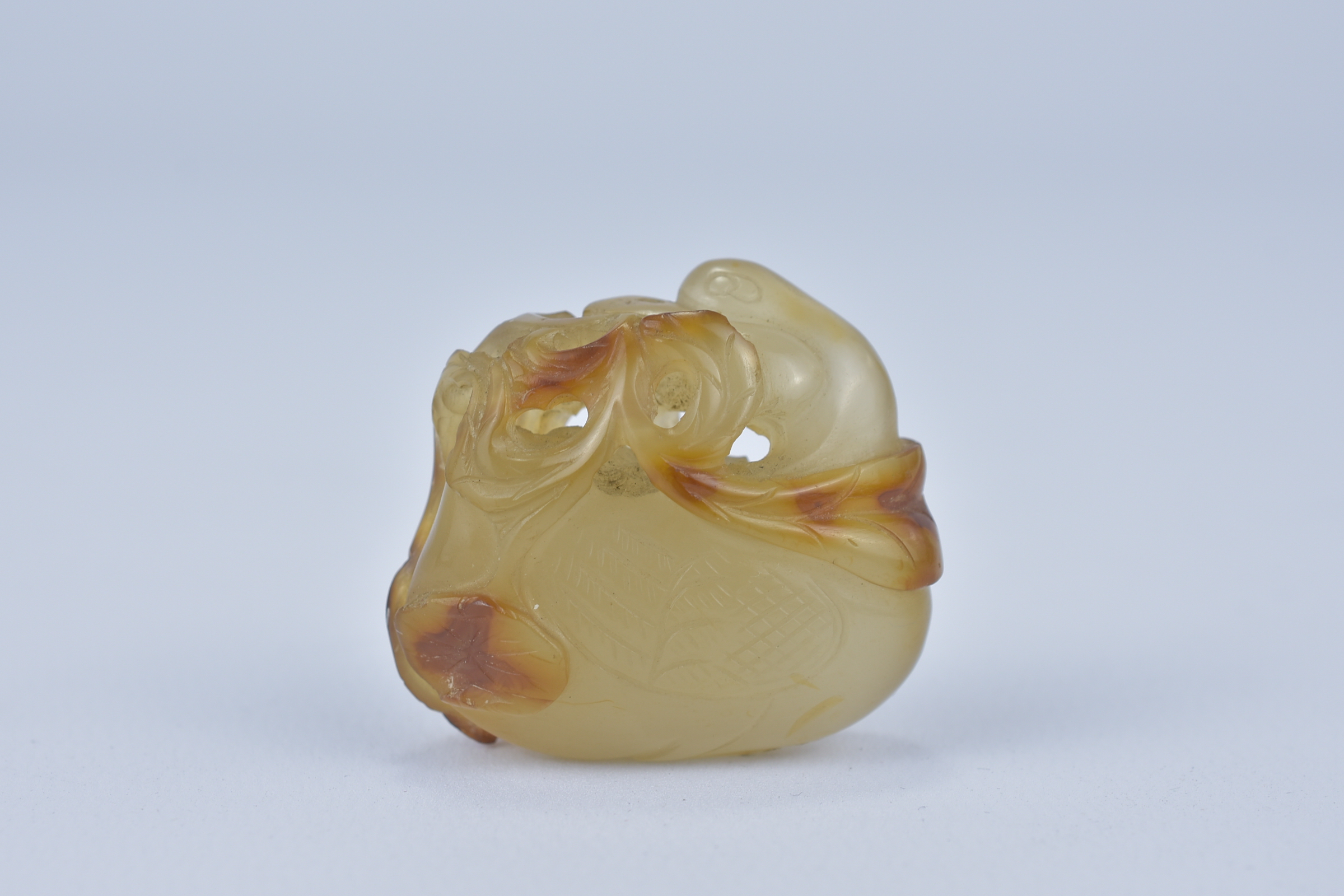 A 19th century Chinese light and dark brown Agate pendant carved as a Duck holding a lotus branch in - Image 2 of 14