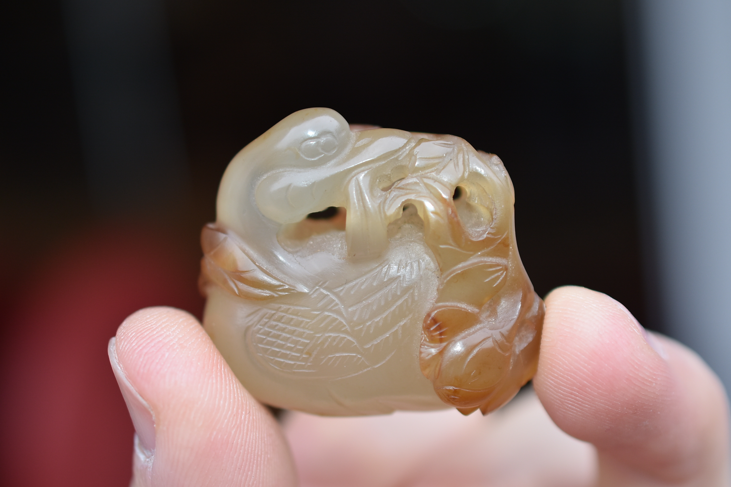 A 19th century Chinese light and dark brown Agate pendant carved as a Duck holding a lotus branch in - Image 5 of 14