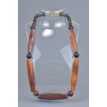 A string of five long agate beads together with twenty small agate beads in a necklace.