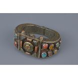 A Tibetan metal bracelet with various stone inserts.