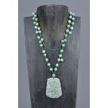 A string of jade beads with a jadeite carved dragon pendant.