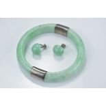A jadeite bangle with silver mounts together with a pair of jadeite  earrings.