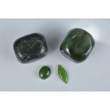 Two spinach jade pebbles together with one cabochon and one diamond-shaped jade.