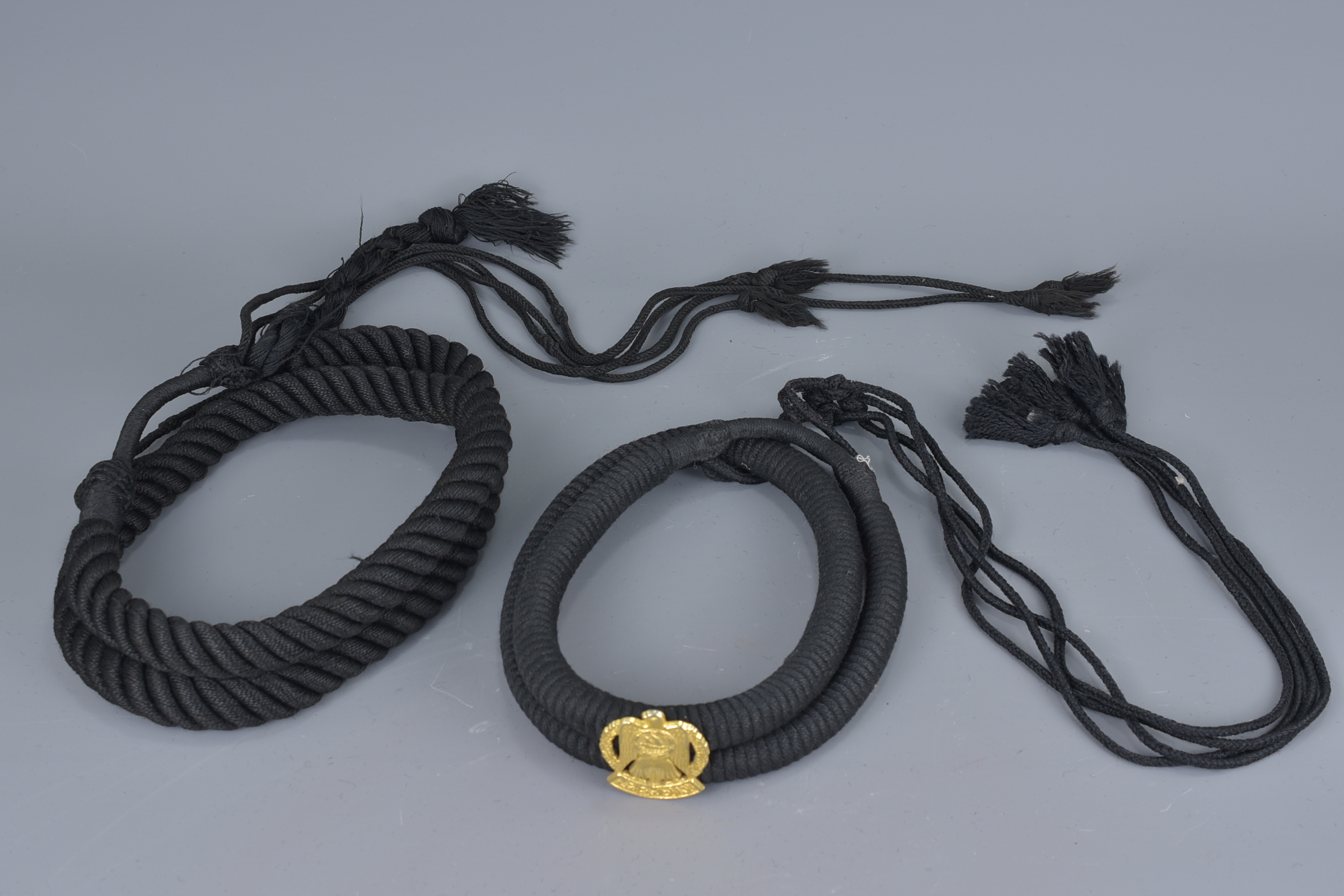 An Islamic braided rope belt and headband fitted with a metal badge of arms with inscription