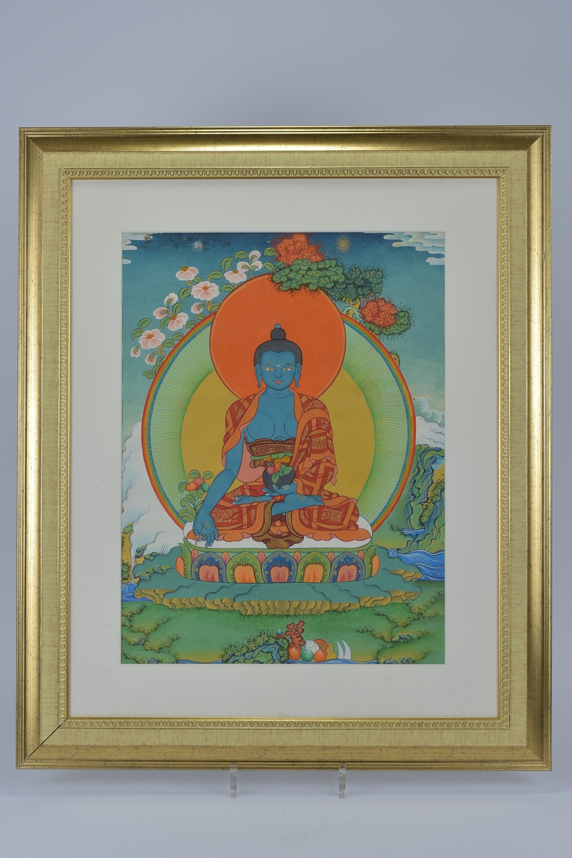 A traditional style Buddhist Thangka painting of Buddha Gautama sitting in a lotus pose holding a bo