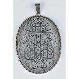 A Persian white metal pendant with inscription.