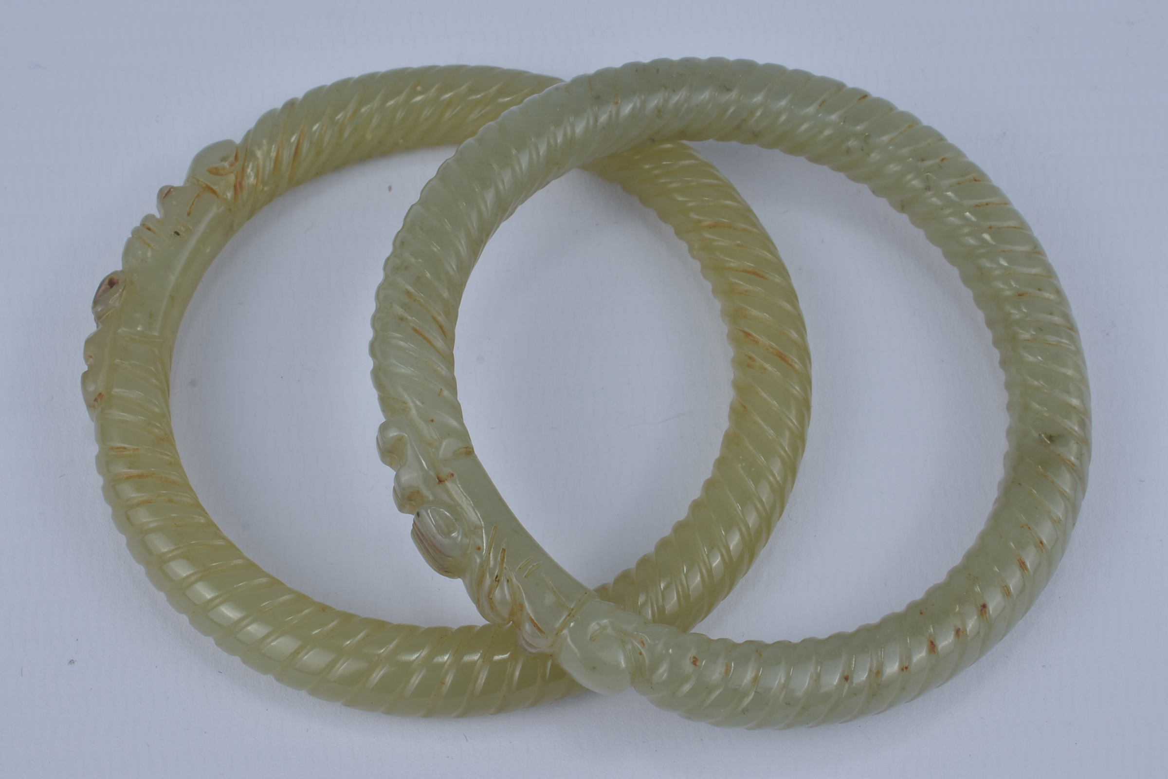 A Pair of Chinese carved Jade Bangles with twist design and dragon  heads. 8cm diameter