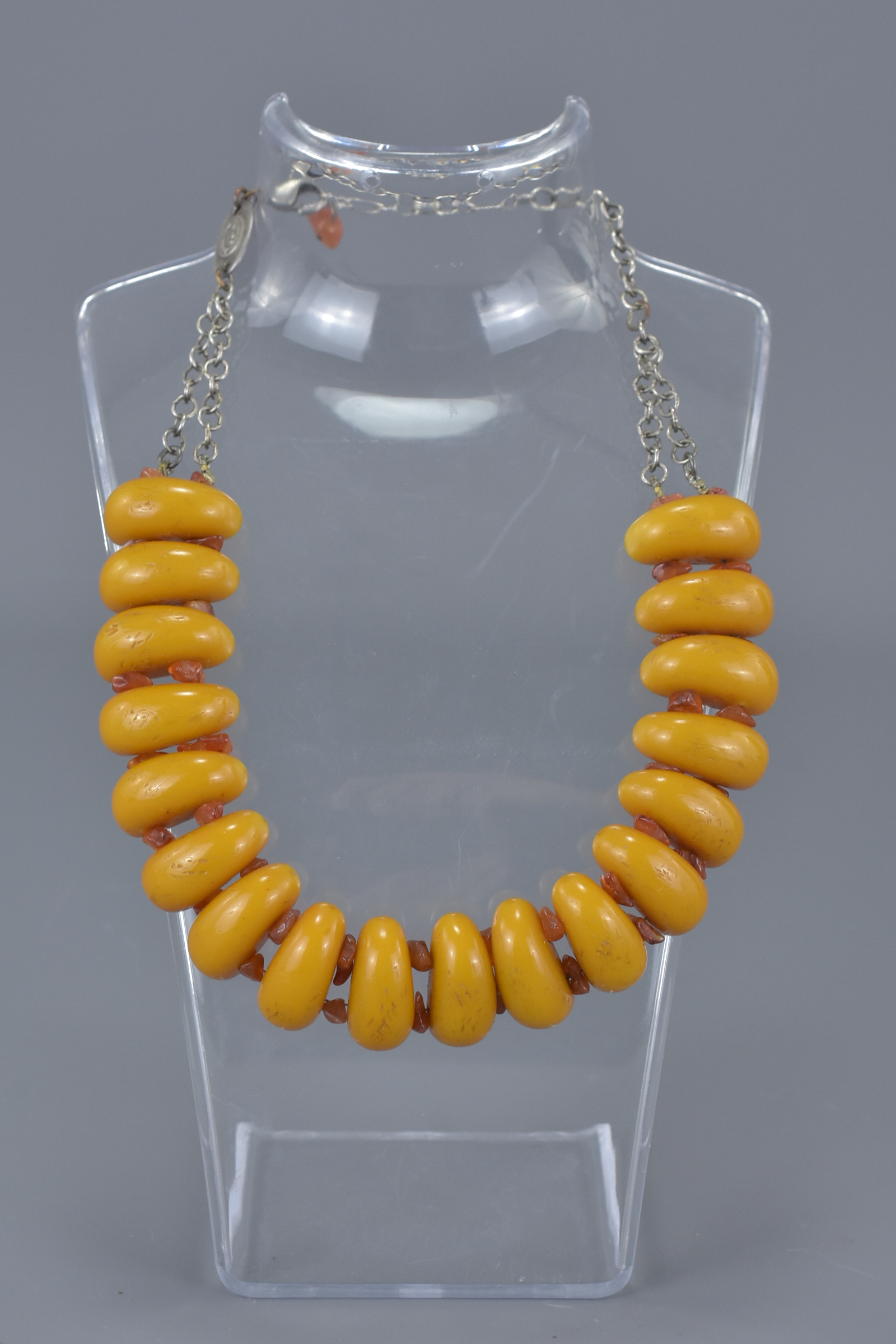 Necklace with 18 Long Amber Coloured Beads spaced with small Amber Chips held on a White Metal Link