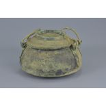 A Chinese Han dynasty or later bronze cooking pot with cover and two handles.16cm height