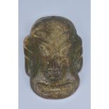 A large archaic style stone mask pendant. 9cm width