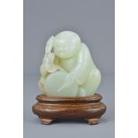 A Chinese 19th century pale celadon jade carving of a boy holding a ruyi sceptre with bat playing a