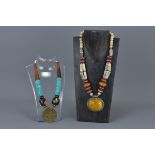 Two Ethnic Necklaces, one with wooden and turquoise coloured beads and large brass disc pendant, the
