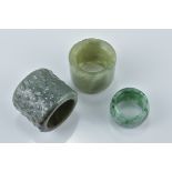 Two Chinese jade archers rings together with a single pale and dark green jadeite ring. Slight chip